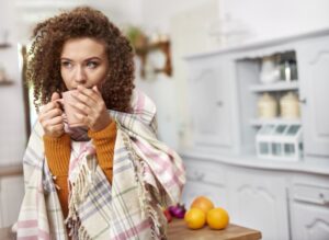 woman-huddled-with-blanket-drinking-from-mug