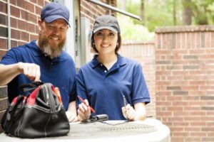 two-technicians-smiling-and-standing-over-outside-ac-unit