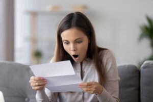 woman-looking-shocked-at-piece-of-paper